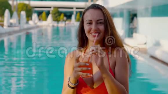 快乐的女人在游泳池里喝异国情调的鸡尾酒视频的预览图