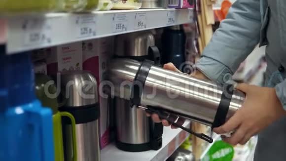 一个年轻的女人在超市里选择了一个钢制热水瓶视频的预览图