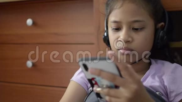 小亚洲女孩使用手机耳机和观看视频视频的预览图