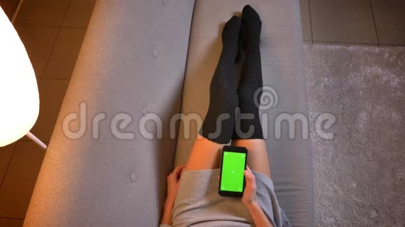 特写拍摄年轻有吸引力的女性健身社交媒体影响者使用手机与绿色屏幕妇女的腿视频的预览图