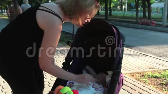 妈妈在散步时和躺在婴儿车里的婴儿玩耍视频的预览图