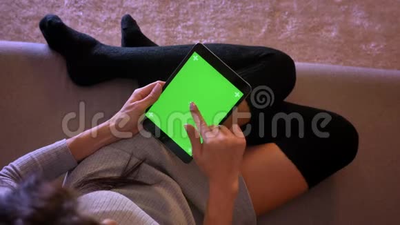 用绿色屏幕特写年轻漂亮女性在平板电脑上浏览的肖像女孩双腿舒适的位置穿袜子视频的预览图