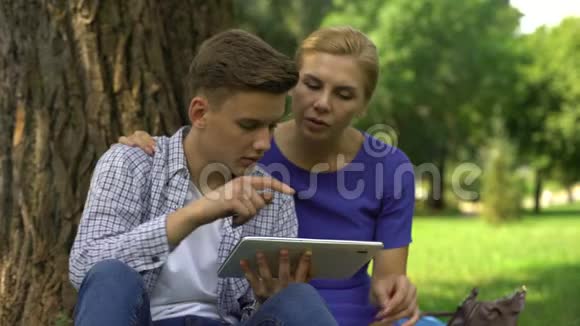 儿子教妈妈如何使用银行和通过平板电脑支付账单现代科技视频的预览图