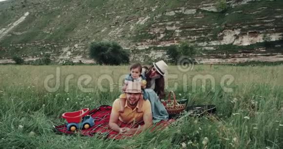 微笑美丽的家庭在野餐玩耍在山中央视频的预览图