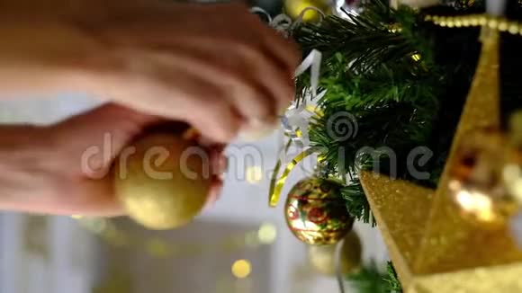 女人手用金色玩具装饰圣诞树背景上的仙女灯视频的预览图