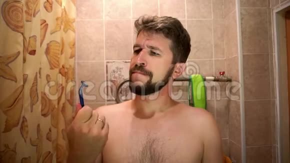 一个留着胡子的男人看着一把一次性剃须刀不满意视频的预览图