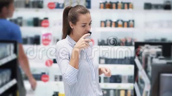 美丽的女孩在化妆品店里选择香水闻它慢动作视频的预览图