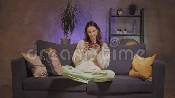 年轻的母子坐在舒适的房间里的沙发上打电话视频的预览图