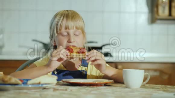 有胃口的小女孩在厨房里吃披萨视频的预览图