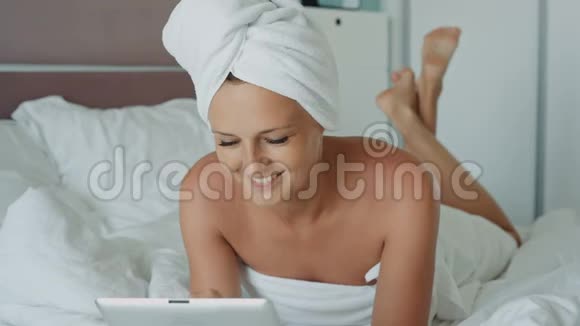 淋浴后使用平板电脑的妇女在酒店房间微笑视频的预览图