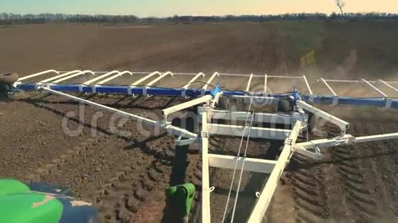从耕耘者的驾驶室到农场肥沃的田野拖拉机犁地用大金属耙土视频的预览图