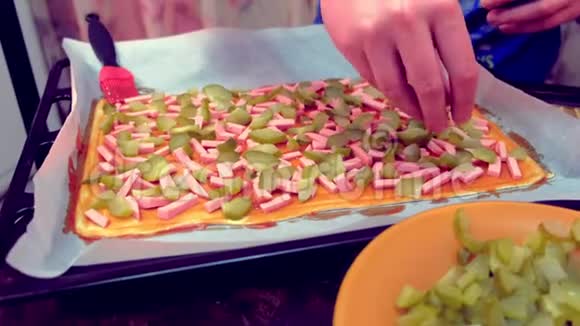 做自制披萨男人把一块腌黄瓜放在面团上配上酱汁和香肠特写视频的预览图