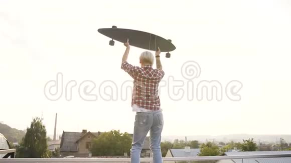 后景年轻的时髦女人与滑板站在屋顶现代滑板公园在夏季日落女孩视频的预览图