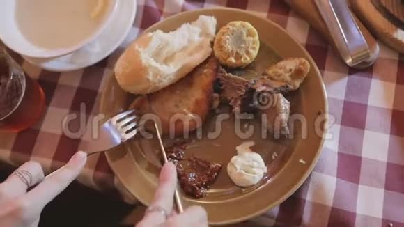 拿着叉子和刀的女人在啤酒店里吃烤土豆和烤肉视频的预览图