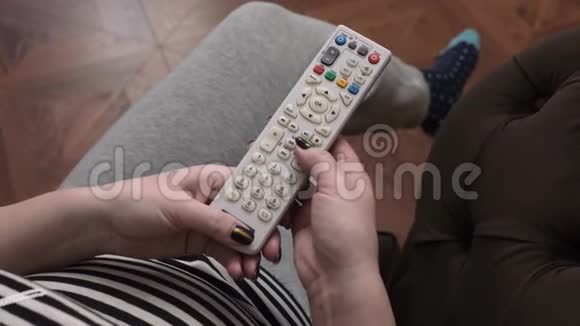 一个女人拿起遥控器按下按钮然后把它拿回来视频的预览图