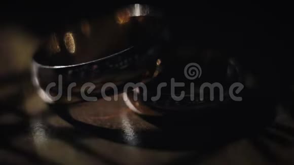 结婚戒指躺在桌子上在黑暗的背景下发光特写视频的预览图