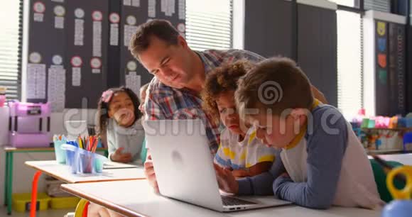 高加索男教师在4k教室用笔记本电脑教授学童的侧视图视频的预览图