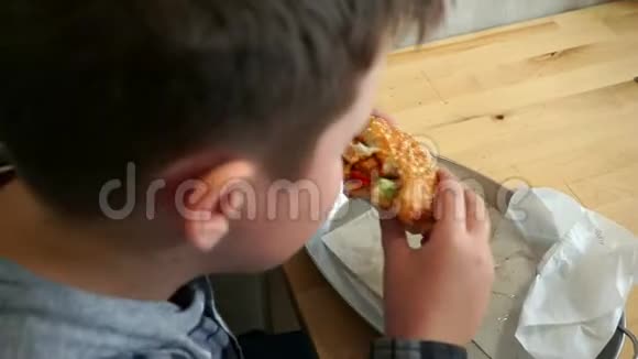一个在咖啡馆里吃汉堡包的少年他饿了从上面看视频的预览图