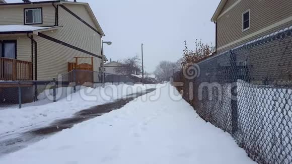 冬天下雪的时候房子之间的住宅走道地下雪景行人路视频的预览图