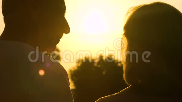 老人亲吻拥抱心爱的女人欣赏浪漫的日落视频的预览图