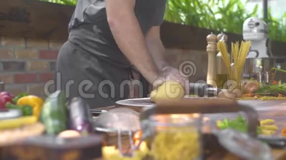 男人在厨房为意大利面食做面团厨师在传统披萨的木桌上捏面团食物视频的预览图
