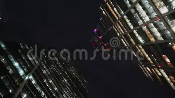 现代玻璃摩天大楼底部视角为直角带旋转晚上视频的预览图