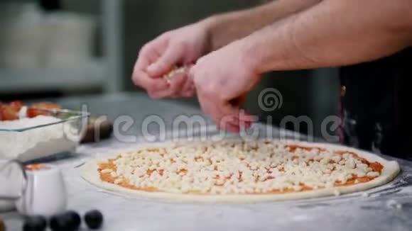 餐厅厨房厨师在披萨上放奶酪把披萨上的奶酪层对齐视频的预览图