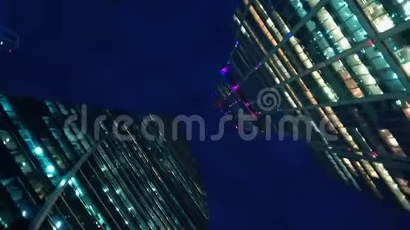 现代玻璃摩天大楼底部视角为直角带旋转晚上视频的预览图