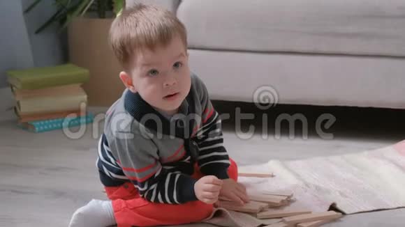 男孩正在用坐在沙发旁边的木块建造一座塔视频的预览图