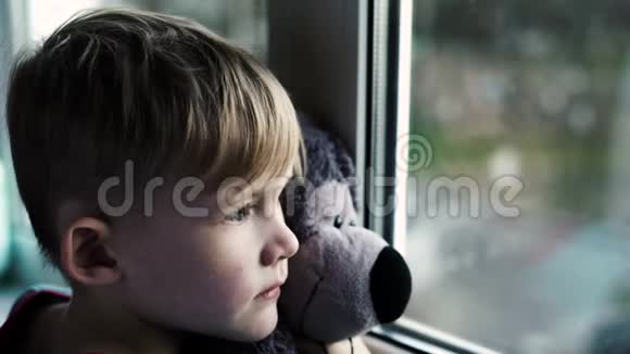 小男孩微笑着看着窗外下雨天小孩从窗户往外看视频的预览图
