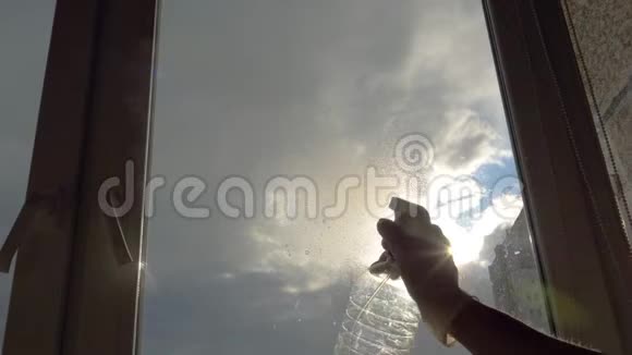 家庭主妇在窗户玻璃清洁剂上喷洒清洁剂并用刷子清洗视频的预览图