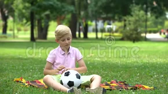 悲伤的男孩孤独地坐在公园里父母给他礼物来支持和振作起来视频的预览图