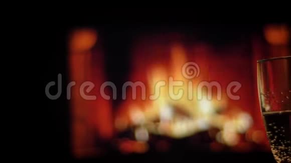 亲密拍摄两只手的朋友在温暖的壁炉旁手里拿着装满香槟的酒杯在室内令人寒心视频的预览图