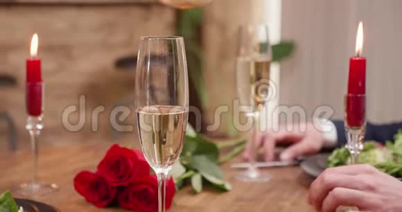 在桌上放着蜡烛和红玫瑰的杯子里倒入香槟视频的预览图