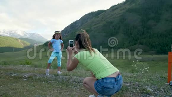 女人在美丽的山景背景上拍摄一个孩子慢动作4k60fps女孩视频的预览图