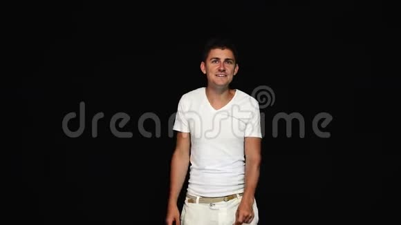 排练的年轻短发男子穿白色t恤和裤子在相机上视频的预览图