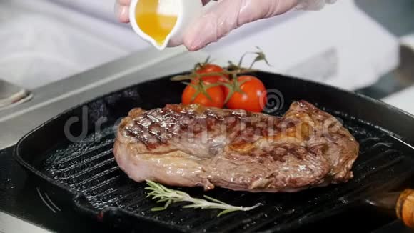 餐厅厨房厨师在锅里煎一块牛排在上面加果汁视频的预览图