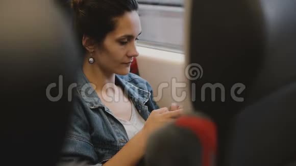 火车上的休闲女乘客坐在舒适的座位上使用智能手机电子商务应用程序看着车窗视频的预览图