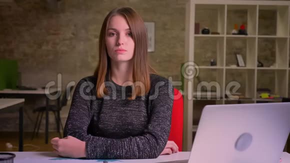 严肃的女孩肖像坐在办公室的笔记本电脑前视频的预览图