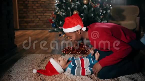 一个快乐的男孩和一个男人在圣诞节的地板上玩得很开心这个伟大的家庭在一起玩得很开心视频的预览图
