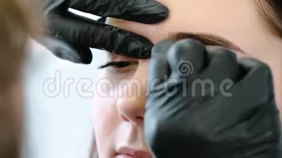 美容师用棉签擦女人的眉毛矫正眉毛前视图特写视频的预览图