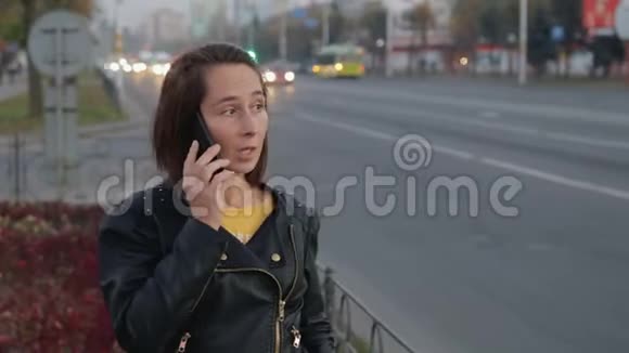 年轻女孩在城市喧嚣的背景下用手机说话bokeh视频的预览图