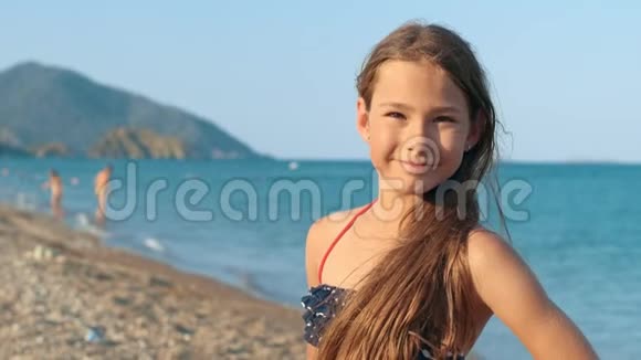 在海滩上微笑的女孩肖像快乐的孩子在度假时用相机摆姿势视频的预览图