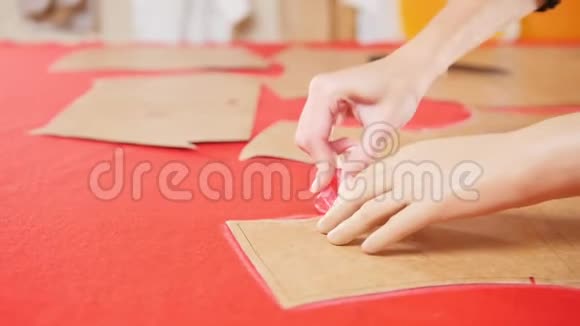 年轻女子在缝纫厂用手臂假体在红布上做素描双手集中视频的预览图