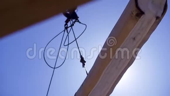 用于建造木屋的带有原木的起重机剪辑吊绳上悬挂的木材重在蓝天背景上视频的预览图