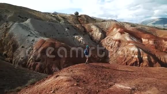 年轻的旅游妇女穿着短裤和一件带背包的衬衫沿着巨大美丽的红色峡谷的边缘走50英尺视频的预览图