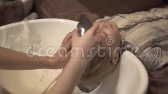理发师手洗小孩发贴在理发店给小男孩洗头儿童理发店沙龙视频的预览图