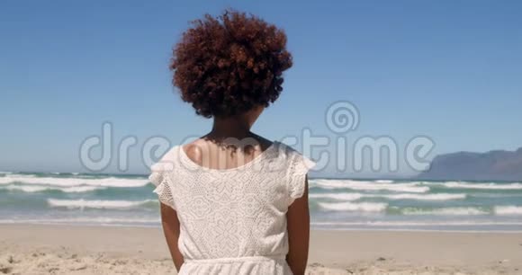 年轻的非裔美国妇女在阳光4k的海滩上放松的后景视频的预览图