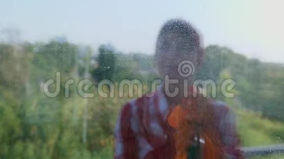 在窗户玻璃上反射微笑的女人戴着手套通过喷洒清洁产品来清洁窗户使用视频的预览图