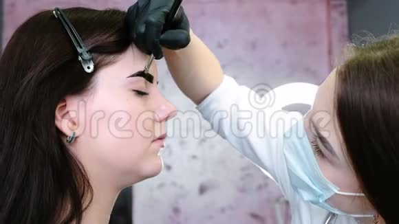 眉毛矫正美容师用刷子在客户眉毛上涂油漆侧视视频的预览图